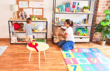 Anaokulunda bir sürü oyuncakla duran güzel öğretmen ve çocuk.