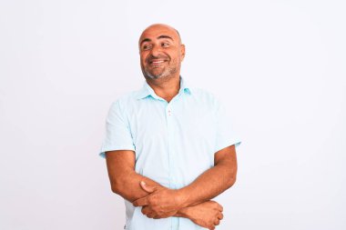 Orta yaşlı yakışıklı bir adam, sıradan bir tişört giyip izole edilmiş beyaz arka planda duruyor. Gülümsüyor ve başka tarafa bakıyor..