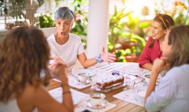 Genç ve güzel bir kız mutlu ve kendinden emin bir şekilde terasta oturmuş bir fincan kahve içiyor.