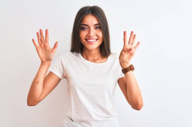 Genç güzel kadın rahat t-shirt izole beyaz arka plan üzerinde duran gösteren ve parmakları ile işaret ederken emin ve mutlu gülümseyerek dokuz.