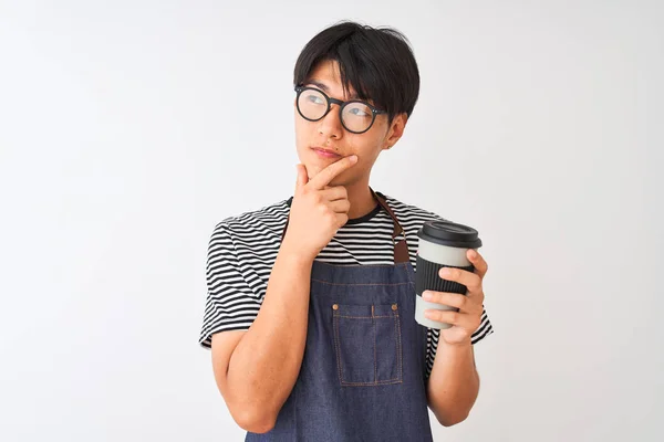 Chinese barista man wearing apron and glasses holding coffee over isolated white background serious face thinking about question, very confused idea