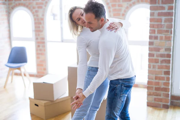 Young beautiful couple dancing at new home around cardboard boxes