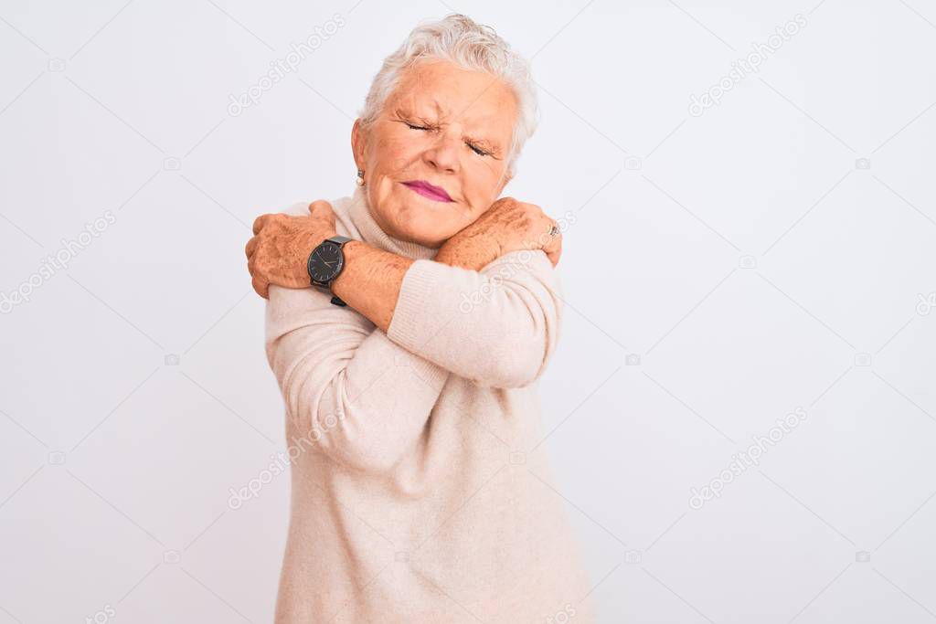 Senior grey-haired woman wearing turtleneck sweater standing over isolated white background Hugging oneself happy and positive, smiling confident. Self love and self care