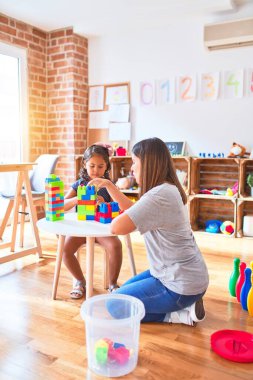 Güzel öğretmen ve küçük kız anaokulunda inşaat bloklarıyla oynuyorlar.