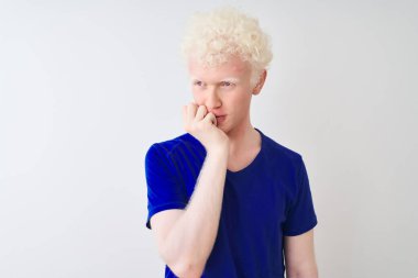 İzole edilmiş beyaz arka planda duran mavi bir tişört giyen genç albino sarışın adam elleri ağız ısıran tırnaklarla gergin ve stresli görünüyor. Endişe sorunu.