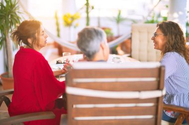 Orta yaşlı kadınlarla buluşup, öğle yemeği yiyip, kahve içiyorlar. Olgun arkadaşlar mutlu bir şekilde gülümsüyor. Güneşli bir günde evde akıllı telefon kullanıyorlar.