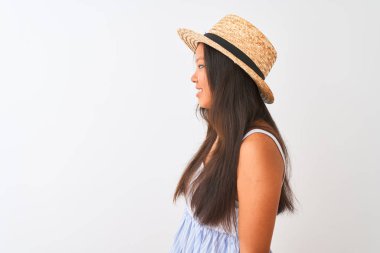 İzole edilmiş beyaz arka plan üzerinde duran çizgili elbise ve şapka giyen genç Çinli kadın yan yana bakıyor, rahat bir görünüm sergiliyor kendine güvenen bir gülümsemeyle doğal bir yüz ifadesi sergiliyor..