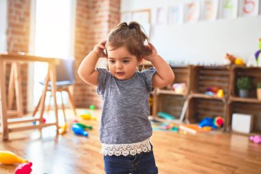 Anaokulunda bir sürü oyuncağın etrafında gülümseyen güzel bir çocuk.