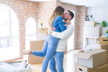 Genç güzel çift sarılma ve karton kutular etrafında yeni evde öpüşme