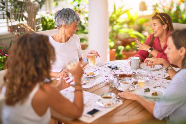 Genç ve güzel bir kız mutlu ve kendinden emin bir şekilde terasta oturmuş bir fincan kahve içiyor.