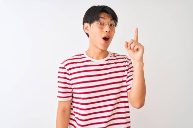 Gözlüklü ve çizgili tişörtlü genç Çinli adam izole edilmiş beyaz arka planda duruyor ve başarılı bir fikri işaret ediyor. Heyecanlı ve mutlu. Bir numara..
