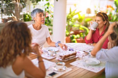 Genç ve güzel bir kız mutlu ve kendinden emin bir şekilde terasta oturmuş bir fincan kahve içiyor.