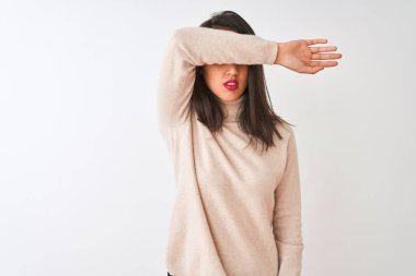 Balıkçı yaka kazak giyen güzel Çinli kadın izole edilmiş beyaz arka planda dikiliyor gözlerini kollarıyla kapatıyor, ciddi ve üzgün görünüyor. Görme, saklama ve reddetme konsepti