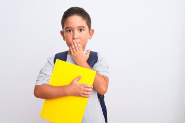 Sırt çantasıyla gezen güzel bir çocuk beyaz arka plan üzerine kitap tutuyor. Ağzı kapalı, hata yaptığı için utancından ağzı açık, korku ifadesi, sessizlikten korkmak, gizli konsept.