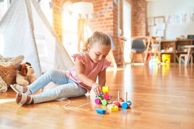 Güzel sarışın küçük kız anaokulunda trenle oynuyor.