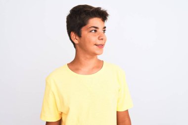 Yakışıklı genç çocuk beyaz soyutlanmış arka planda duruyor. Yüzünde gülümseme, doğal bir ifade ile yan yana bakıyor. Kendinden emin gülen.