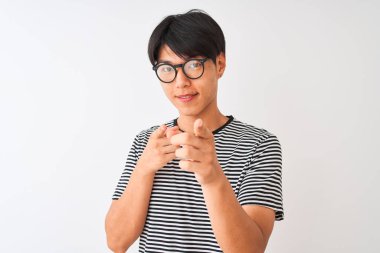 Gözlüklü ve donanma tişörtlü Çinli bir adam izole edilmiş beyaz arka planda durmuş mutlu ve komik yüzlü parmaklarını kameraya doğrultuyor. İyi enerji ve titreşimler.