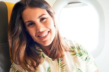 Young traveller woman sitting inside plane at the airport with sky view from the window clipart