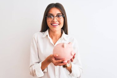 Güzel bir iş kadını gözlüklü, kumbarasını izole edilmiş beyaz arka planda tutan mutlu bir yüzü olan, kendine güvenen bir gülümsemeyle dişlerini gösteren bir kadın.