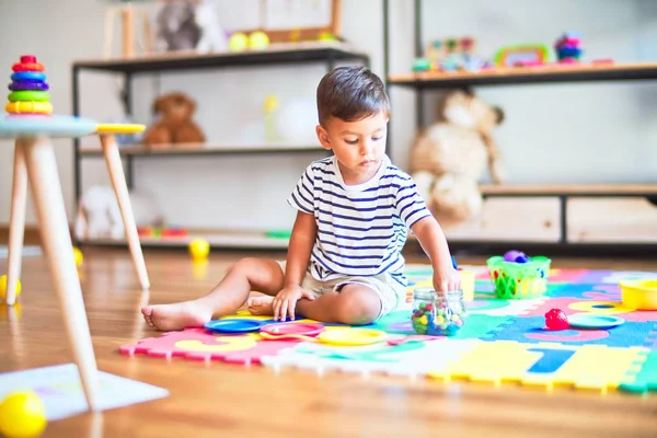 Piękny Mały Chłopiec Siedzi Puzzle Jedząc Małe Kolorowe Kulki Czekolady — Zdjęcie stockowe