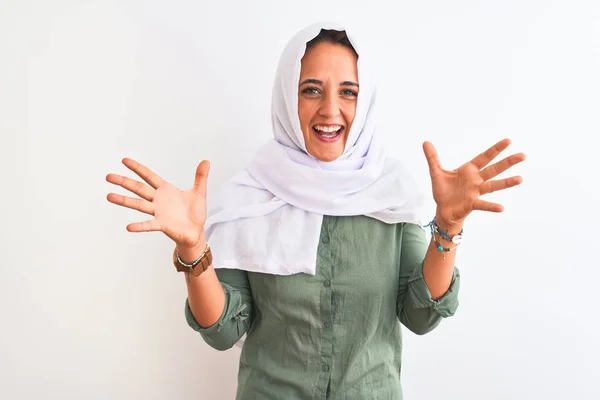孤立した背景の上に伝統的なイスラム教徒のヒジャーブを身に着けている若い美しいアラブの女性は 狂気を祝い 腕を上げ 興奮して叫んで目を開けて成功に驚いています 勝者のコンセプト — ストック写真