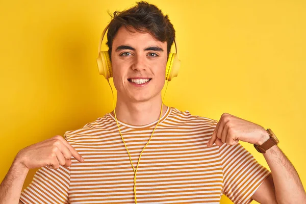 Adolescente Menino Usando Fones Ouvido Sobre Fundo Amarelo Isolado Olhando — Fotografia de Stock