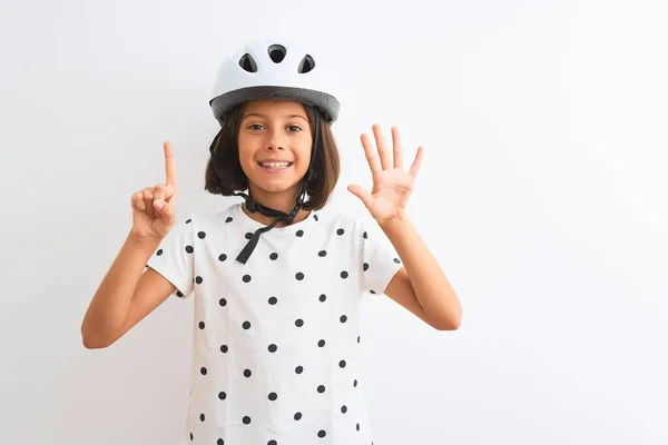漂亮的小女孩戴着安全自行车头盔 站在孤独的白色背景上 带着六号手指指尖 面带微笑 自信而快乐 — 图库照片