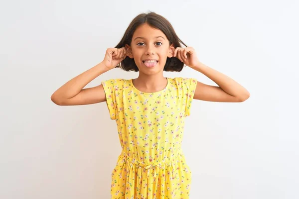 孤立した白い背景の上に立つ黄色の花のドレスを身に着けている若い美しい子供の女の子指で耳を引く笑顔 面白いジェスチャー オーディション問題 — ストック写真