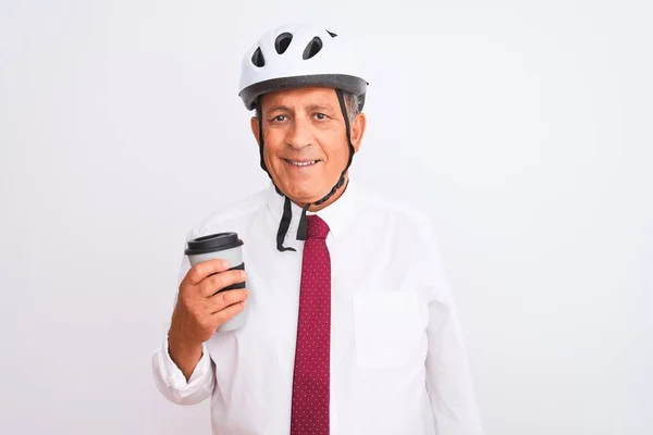 年长的商人戴着自行车头盔 在孤独的白色背景下喝咖啡 脸上挂着快乐的表情 脸上挂着自信的微笑 露出牙齿 — 图库照片