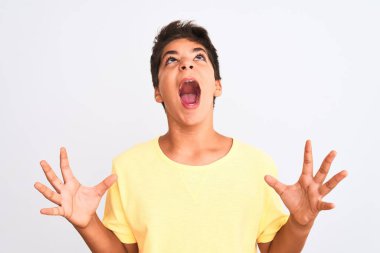 Yakışıklı genç çocuk beyaz arka planda duruyor çılgın ve kızgın bir şekilde bağırıyor ve agresif bir ifade ve kollarla bağırıyor. Hayal kırıklığı konsepti.