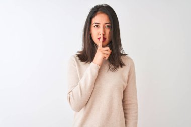 Balıkçı yaka kazak giyen güzel Çinli kadın izole edilmiş beyaz arka planda dikiliyor ve sessiz olmak istiyor. Sessizlik ve gizli konsept.