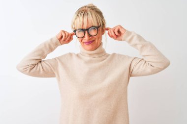 Boğazlı kazak ve gözlük takan orta yaşlı bir kadın yüksek sesli müzik sesi için kulaklarını parmaklarıyla kapatıyor. Sağır kavramı.