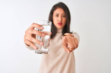 Genç, güzel bir Çinli kadın izole edilmiş beyaz arka planda durup kamerayı işaret ediyor ve sen, el işareti, ön taraftan pozitif ve kendinden emin bir hareket.