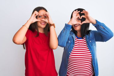 İzole edilmiş beyaz arka plan üzerinde duran, el ve parmaklarıyla kalp şeklinde gülümseyen gündelik giysiler giyen genç ve güzel kadınlar.