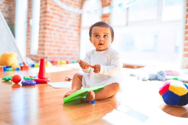 Güzel bebek anaokulunda renkli oyuncakların etrafında mutlu manyetik karatahtaya çizim yapıyor.