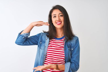 İzole edilmiş beyaz arka plan üzerine çizgili t-shirt ve kot gömlek giyen genç Çinli bir kadın. Büyük ve büyük boylarda işaret eden el kol işareti, ölçü sembolü. Kameraya bakıp gülümsüyor. Ölçüm konsepti.