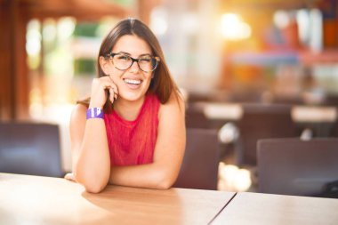 Genç, güzel bir kız mutlu ve kendinden emin bir şekilde parktaki sandalye restoranında oturuyor.