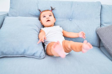 Anaokulunda kanepedeki renkli oyuncakların yanında mutlu bir bebek.