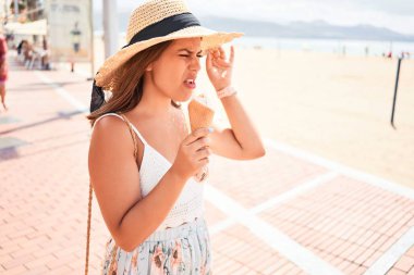 Yazın güneşli bir gününde kumsalda dondurma yiyen güzel bir kadın.