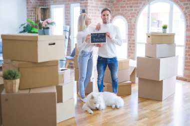 Karton kutuların etrafındaki yeni evlerinde ellerinde karatahtayla bekleyen genç ve güzel bir çift.