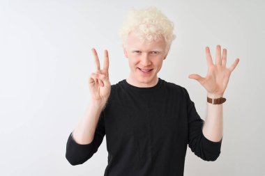 Siyah tişörtlü genç albino adam izole edilmiş beyaz arka plan üzerinde duruyor ve yedinci parmaklarını gösterirken kendinden emin ve mutlu bir şekilde gülümsüyor..