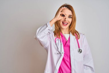 Kafkasyalı doktor kadın pembe steteskop takıyor. El hareketleriyle gülümsüyor ve mutlu yüzüyle parmaklarının arasından bakıyor..