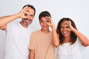 Üç kişilik aile, anne, baba ve oğul beyaz soyutlanmış arka planda duruyorlar. El hareketleriyle gülümseyerek, gözleriyle mutlu yüzlerle bakıyorlar..