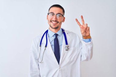 Arka planda steteskop takan genç doktor kameraya bakıp zafer işareti yaparken gülümsüyor. İki numara..