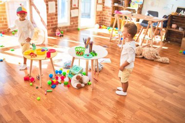 Anaokulunda bir sürü oyuncakla oynayan sevimli sarışın ikizler.