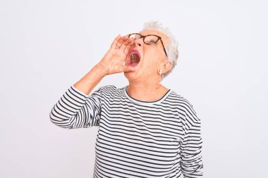 Üst düzey gri saçlı kadın, izole edilmiş beyaz arka planda çizgili donanma tişörtü gözlüğü takıyor ve el ele tutuşarak bağırıyor. İletişim konsepti.