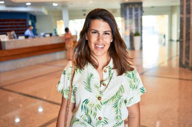 Genç ve güzel bir kadın gülümseyerek tatillerde otel odasında dikiliyor.