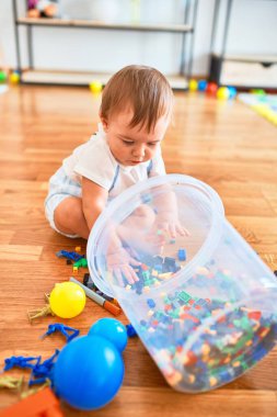 Anaokulunda bir sürü oyuncakla oynayan sevimli bir çocuk.