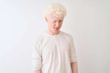 Gündelik tişört giyen genç albino adam izole edilmiş beyaz arka planda dikiliyor kameraya seksi bir ifadeyle bakıyor, neşeli ve mutlu bir yüzle..