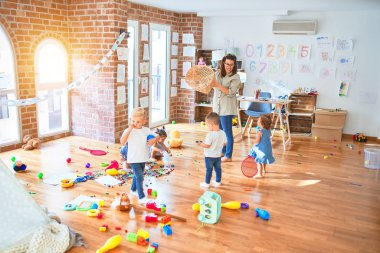 Güzel öğretmen ve bir grup çocuk anaokulunda bir sürü oyuncakla oynuyorlar.
